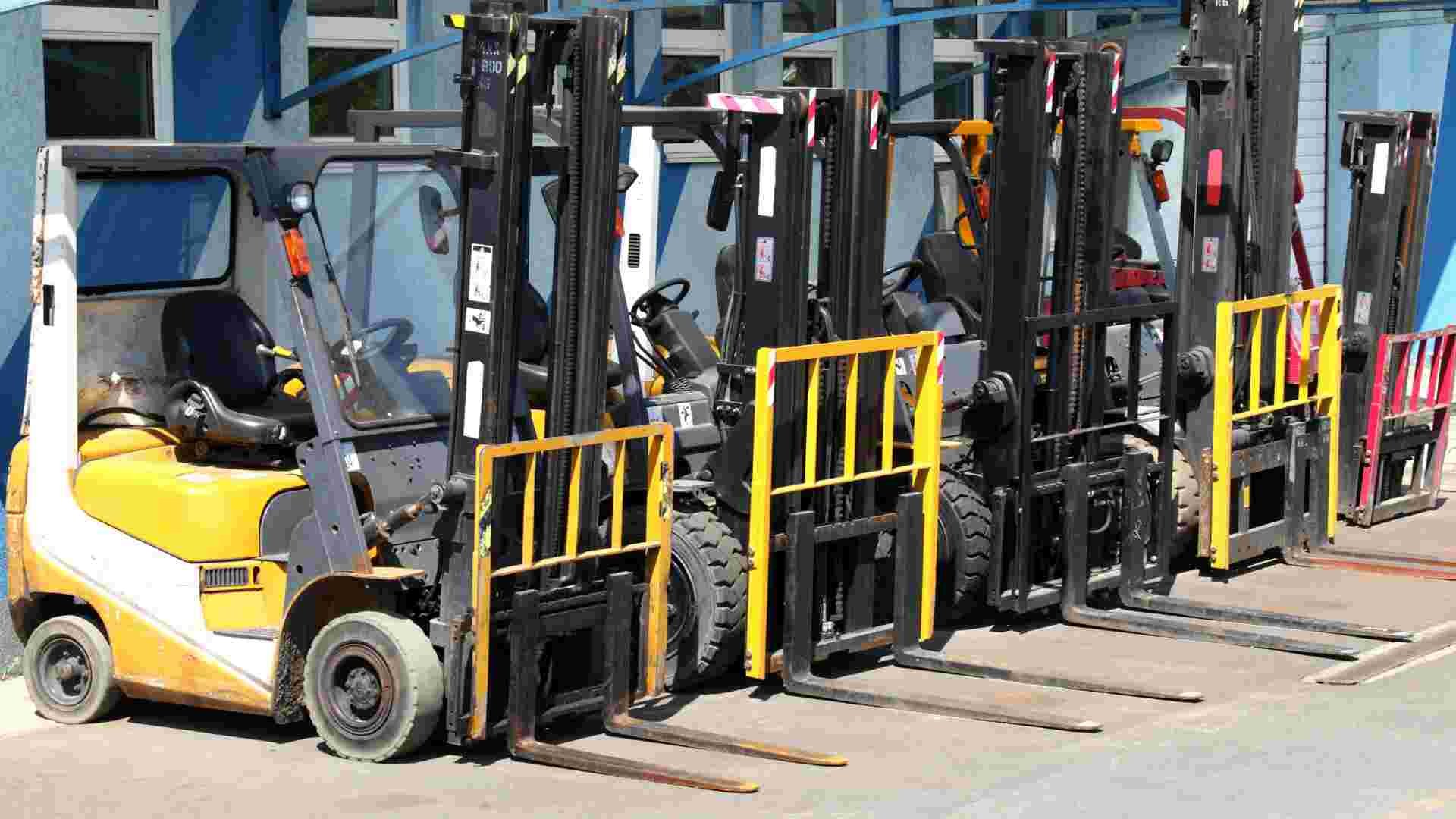 A series of forklifts lined up in a work yard