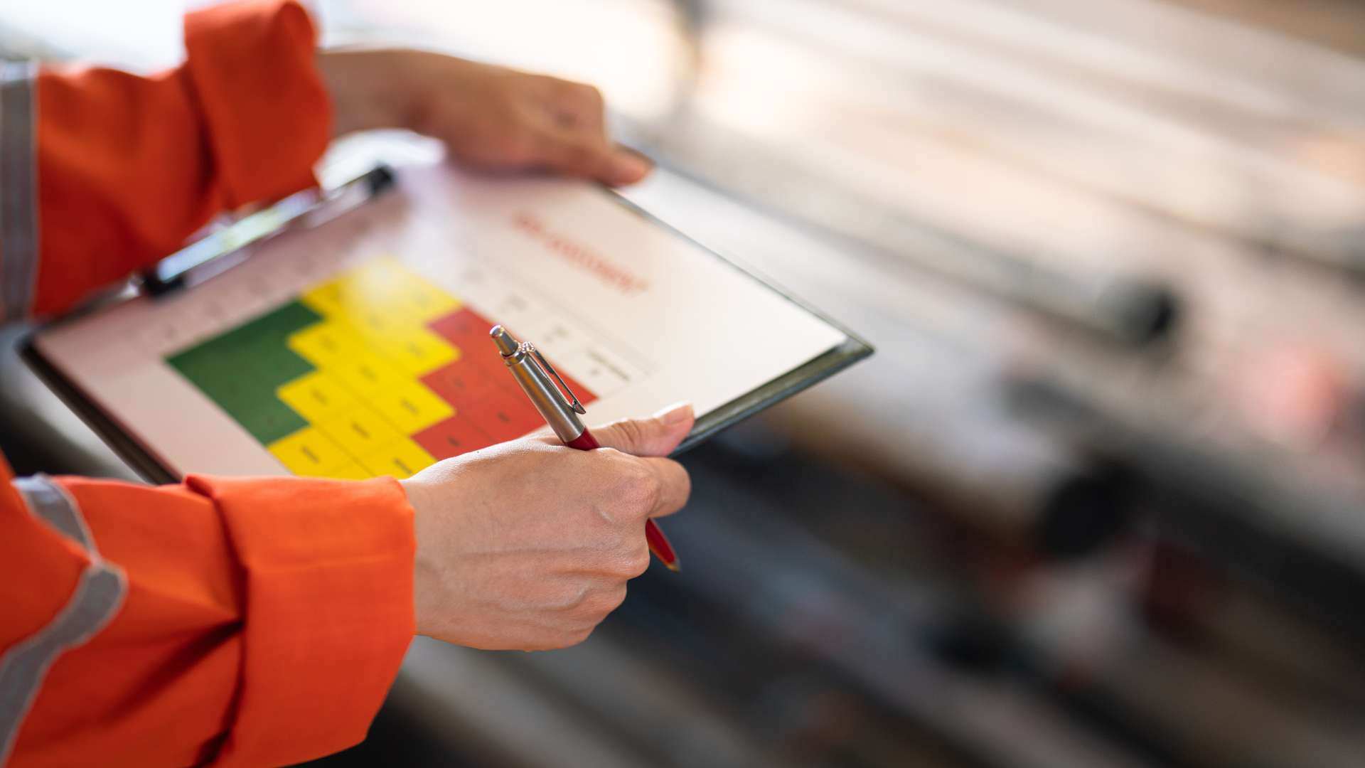 Close up of a person viewing a risk assessment with a risk matrix on a clipboard