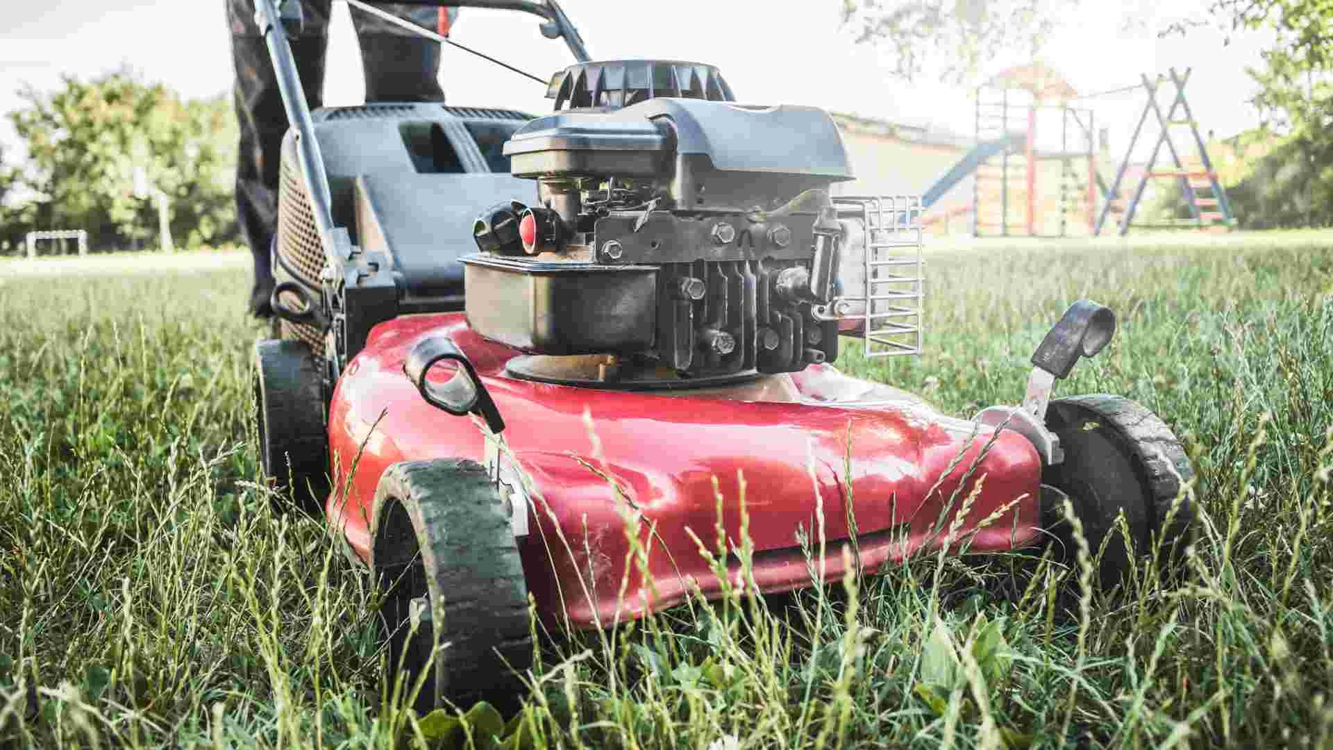 Close up of a red and black compact lawn mower in a residential yard