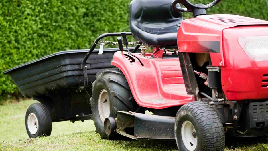 Close up of a red and black ride on lawn mower towing an attachment